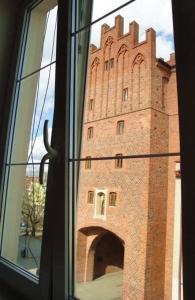 een raam met uitzicht op een hoog bakstenen gebouw bij Apartament Staromiejska in Olsztyn