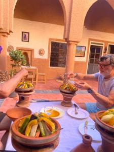 two people sitting at a table with food on it at Riad Nkob in Nkob