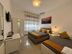 a bedroom with two beds and a desk and a television at Casa Duca D'aosta in Mestre
