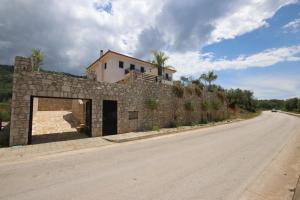 a building on top of a stone wall on the side of a road at Vila Mario Himare in Himare