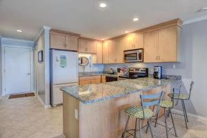 een keuken met een aanrecht en twee barkrukken bij Queen's Grant A-201 in Topsail Beach