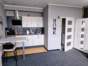 a kitchen with white cabinets and a table with chairs at Apartament Na Reymonta in Starogard Gdański +2 photos