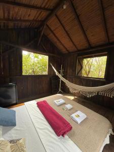un lit dans une chambre en bois avec un hamac dans l'établissement Ecocentro Brasil - Choupana Panorâmica, à São Pedro