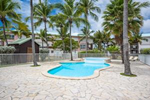 a pool with palm trees in front of a building at Atlantique Créole - Crystal Beach, Saint-François in Saint-François