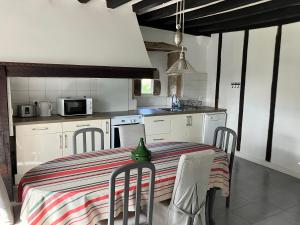 een keuken met een tafel en stoelen en een keuken met witte kasten bij Ancienne maison basque au calme au pied de la Rhune in Sare