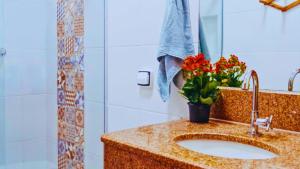 a bathroom with a sink with a vase of flowers at RES FLATS ANGELIM II, SUPERIOR, 2 QUARTOS c AR, CENTRO in Itacaré +33 photos