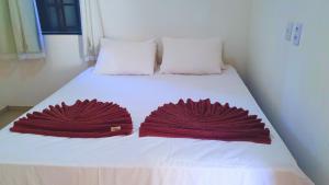 two red towels are on a white bed at RES FLATS ANGELIM II, SUPERIOR, 2 QUARTOS c AR, CENTRO in Itacaré