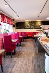 Hotel Dünenburg في فيسترلاند: مطعم به كراسي حمراء وسبورة على الحائط