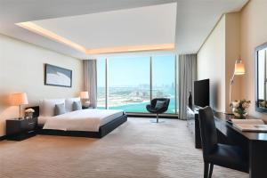 a hotel room with a bed and a desk and window at Kempinski Residences & Suites, Doha in Doha