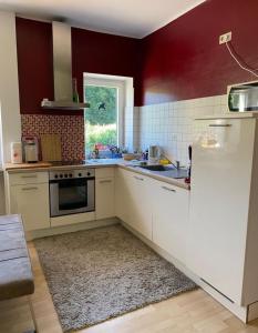 a kitchen with white cabinets and red walls at Haus Glücksmomente Bostalsee in Nohfelden