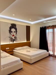 two beds in a room with a painting on the wall at Fori's rooms in Himare