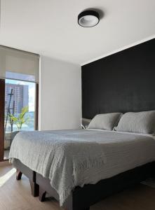 a bedroom with a large bed with a black wall at Departamento Centro moderno con balcón in Temuco +13 photos