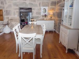 a dining room with a table and white chairs at Casa da Gandarela in Soajo