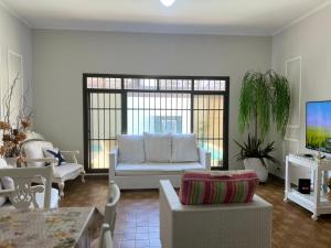 a living room with a couch and a tv at Uma Quadra do MAR Com PISCINA, Churrasqueira, 2 Vg de Garagem e 3 Quartos!!! in Praia Grande