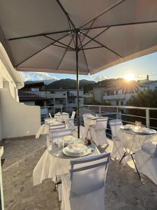 a patio with white tables and chairs with an umbrella at 5 Zimmer Rooms ''Rosa'' in Siniscola