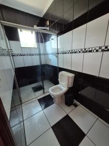 a bathroom with a toilet and black and white tiles at Casa shalom in Serra Negra