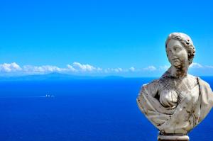 Eine Statue einer Frau, die vor dem Meer steht. in der Unterkunft Hotel Villa Cimbrone in Ravello