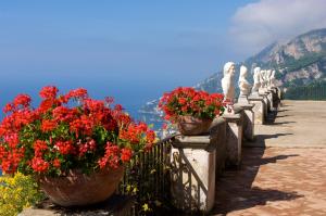 eine Reihe Blumentöpfe auf einem Zaun mit Blumen in der Unterkunft Hotel Villa Cimbrone in Ravello