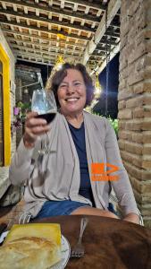 Eine Frau, die an einem Tisch sitzt und ein Glas Wein hält. in der Unterkunft Casa de Meg Charme e Natureza na Serra Negra in Bezerros + 76 Fotos