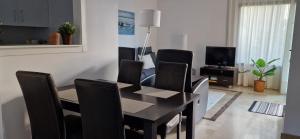a dining room table with black chairs and a television at Casa Colina Roda Golf in San Javier