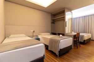 a hotel room with two beds and a table with a chair at Ingleses Park Hotel in Florianópolis +126 photos