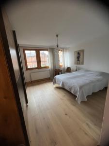 a bedroom with a white bed and a wooden floor at Villars SWISS Alpes in Villars-sur-Ollon