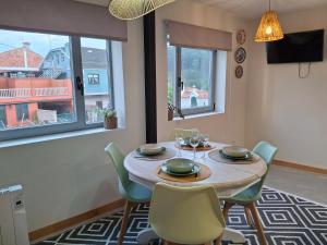 Un comedor con mesa y sillas y ventanas. en Casa Ulloa, en Marín