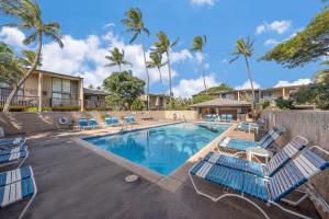 a swimming pool with blue lounge chairs and palm trees at Just Steps to Beach with 2 King Beds and Centrally Located in Kihei
