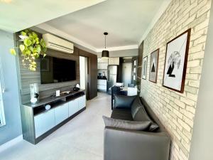a living room with a couch and a tv and a brick wall at Apartamento frente mar in Balneário Camboriú