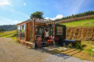 a small wooden house with a bench and plants at Container-house - Serra da Mantiqueira - MG in Toledo
