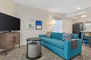 a living room with a blue couch and a tv at Sonesta ES Suites Torrance Redondo Beach in Torrance