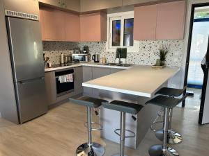 a kitchen with pink cabinets and a counter with stools at Athens Riviera, Modern Vouliagmeni Flat at Cape of Lemos in Athens