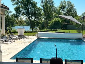 a swimming pool with an umbrella and chairs at Chez Saliha et Serge in Lamarche-sur-Saône