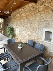 a wooden table with chairs and a stone wall at Villa Doce in Puentecesures