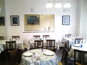 a dining room with tables and chairs and a mirror at Hotel Aurora in Loano