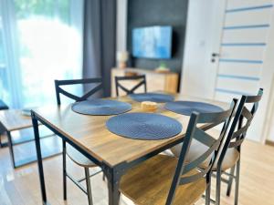 a wooden table with four chairs around it at Apartament AGAT Dziwnówek EPapartamenty in Wrzosowo