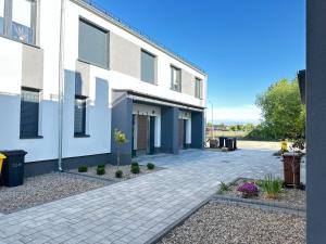 a white building with a brick driveway at Apartament AGAT Dziwnówek EPapartamenty in Wrzosowo