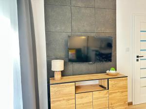 a tv sitting on top of a wooden entertainment center at Apartament AGAT Dziwnówek EPapartamenty in Wrzosowo +162 photos