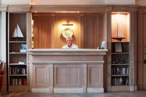 un homme debout derrière un bar dans une bibliothèque dans l'établissement Hotel Poseidon, à Terracine