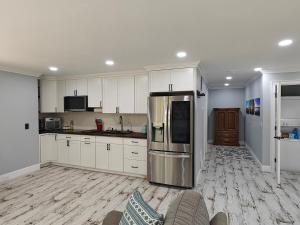 a kitchen with white cabinets and a stainless steel refrigerator at Bayfront & nature preserve! in Riverhead