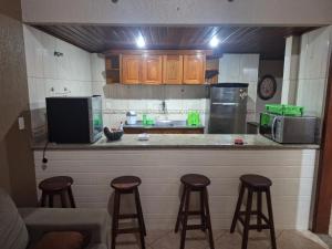 a kitchen with three bar stools and a counter top at Casa Serra Macaé in Água Boa