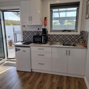 a white kitchen with a sink and a microwave at Kadi House - Unit 1 in Wynyard