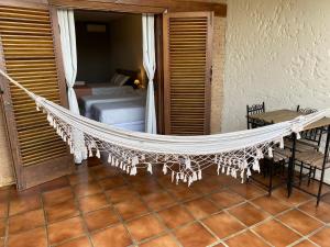 a hammock in a room with a bed and a table at El Shadday Pousada Boutique in Ubatuba