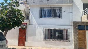 a white building with a dog in a cage at Hospedaje Mar de Perlas in Iquique