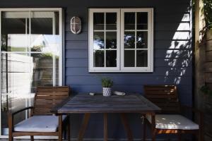 a wooden table and chairs on a blue house at Cranford Cottages and Motel in Christchurch