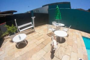Un perro de pie junto a dos mesas y una piscina. en hostel Rep MADAGASCAR, en Florianópolis