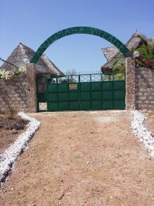 a green gate in a field with a dirt road at Anjumasa Village in Watamu