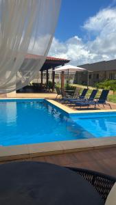 een groot zwembad met stoelen en een tafel bij POUSADA RECANTO DAS ÁGUAS Ville in Santo Amaro