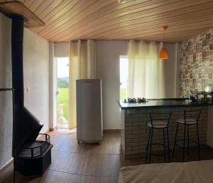 a kitchen with a refrigerator and a counter with stools at Loft 3 Sítio Cachoeiras do Caledônia in Nova Friburgo