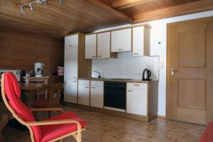 una cocina con armarios blancos y una silla roja en Ferienwohnung Achten, en Waidring